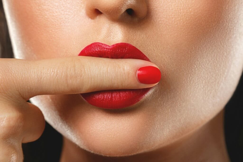 Beauty and cosmetics. Female mouth and nails with red manicure and lipstick.